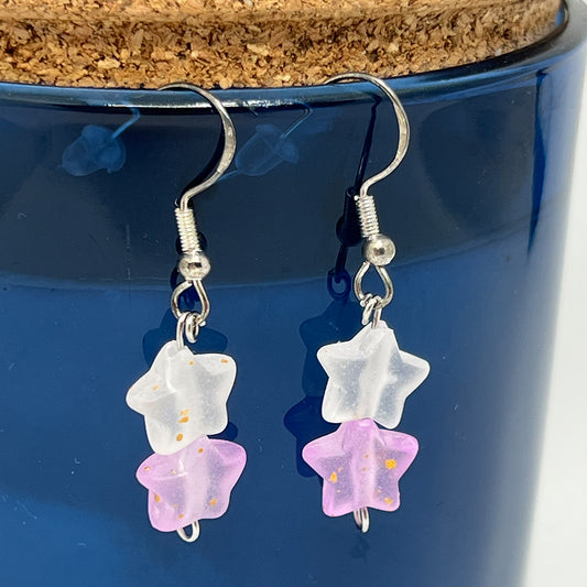 Star-shaped earrings with white and pink stars on a blue background