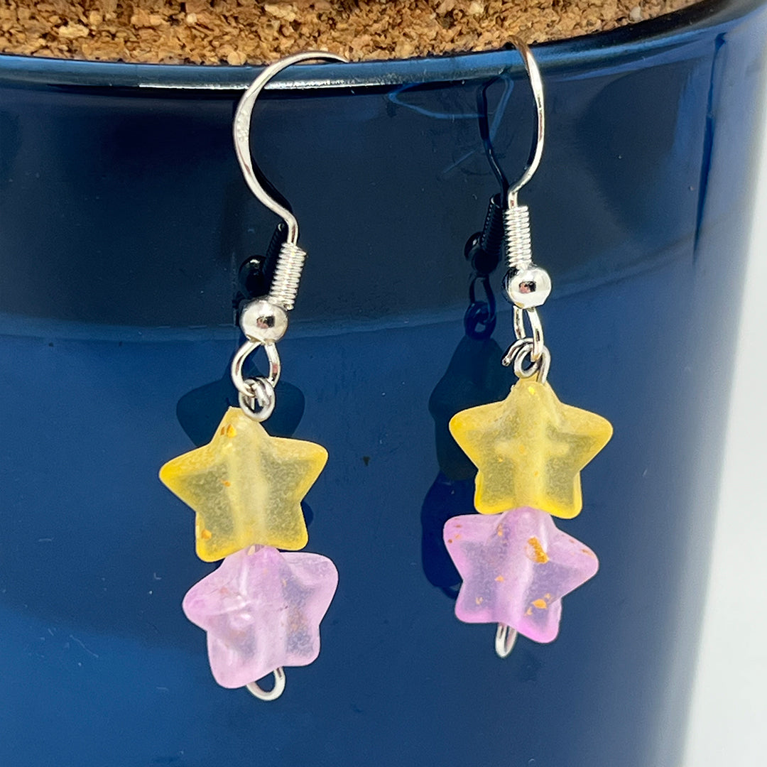 Star-shaped earrings with yellow and pink stars on a blue background