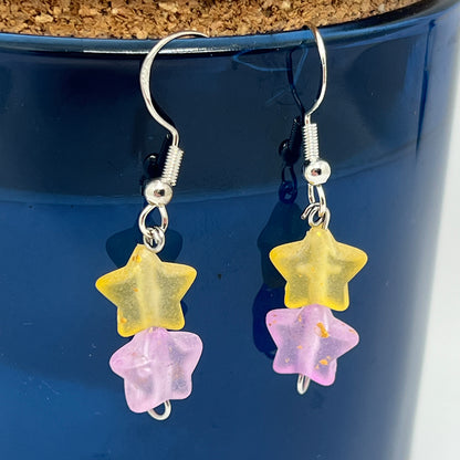 Star-shaped earrings with yellow and pink stars on a blue background